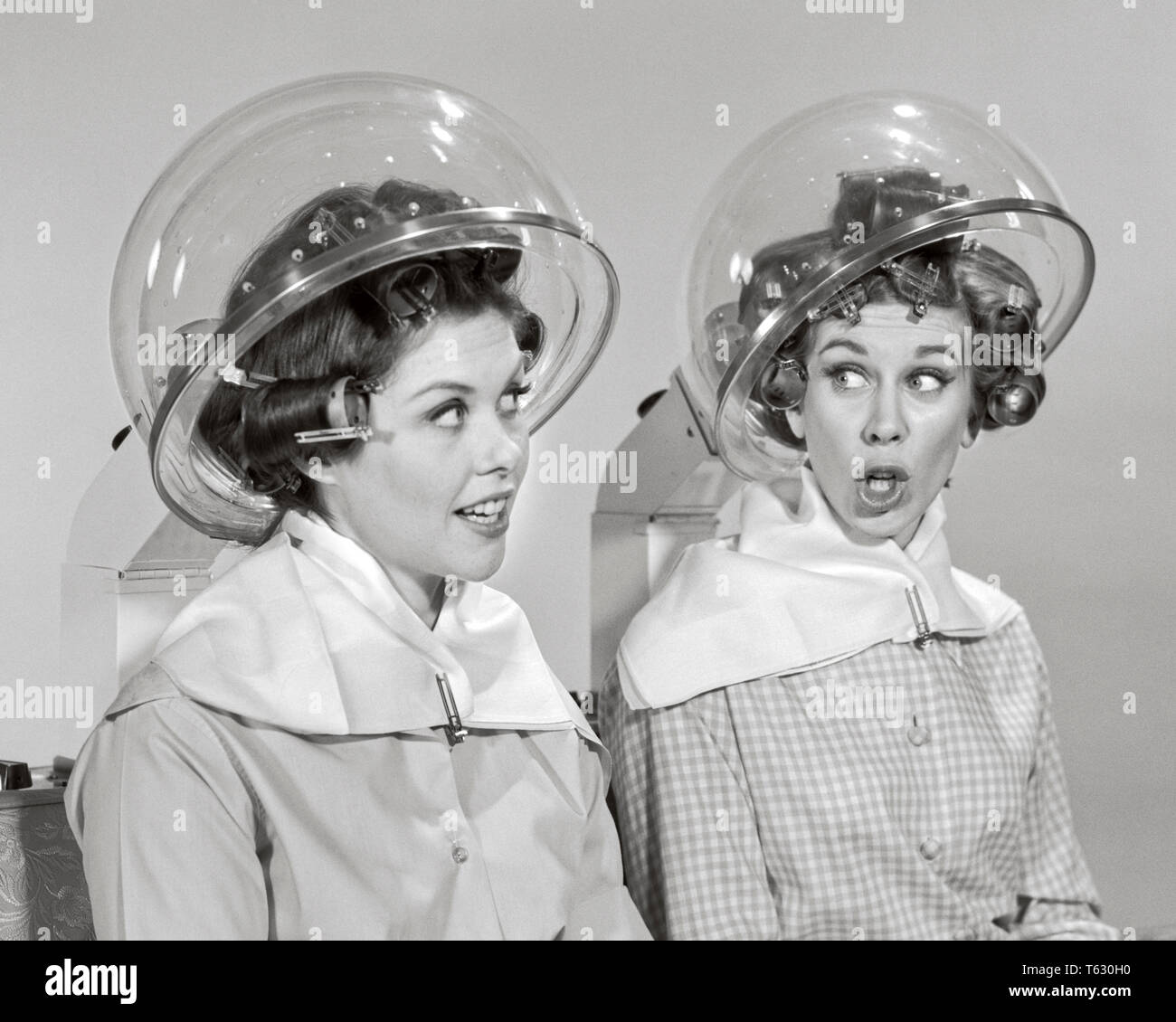 1960s Two women rollers curler in their hair sitting under hair salon dryers talking gossiping - s15079 HAR001 HARS SALON INFORMATION HOOD LIFESTYLE GROWNUPS FEMALES GOSSIP STUDIO SHOT GROWNUP COPY SPACE FRIENDSHIP HALF-LENGTH LADIES PERSONS GROWN-UP SPEAK PAIRS SIBLINGS CONFIDENCE SISTERS GOSSIPING B&W ROLLERS CURLERS HAPPINESS DISCOVERY LEISURE THEIR NETWORKING IN OPPORTUNITY SIBLING SMILES GOSSIPS CONNECTION CONCEPTUAL DRYERS HAIR DRYER BEAUTY PARLOR STYLISH CURLER PLASTIC DOME COOPERATION HAIR SALON MID-ADULT MID-ADULT WOMAN TOGETHERNESS YOUNG ADULT WOMAN BLACK AND WHITE Stock Photo