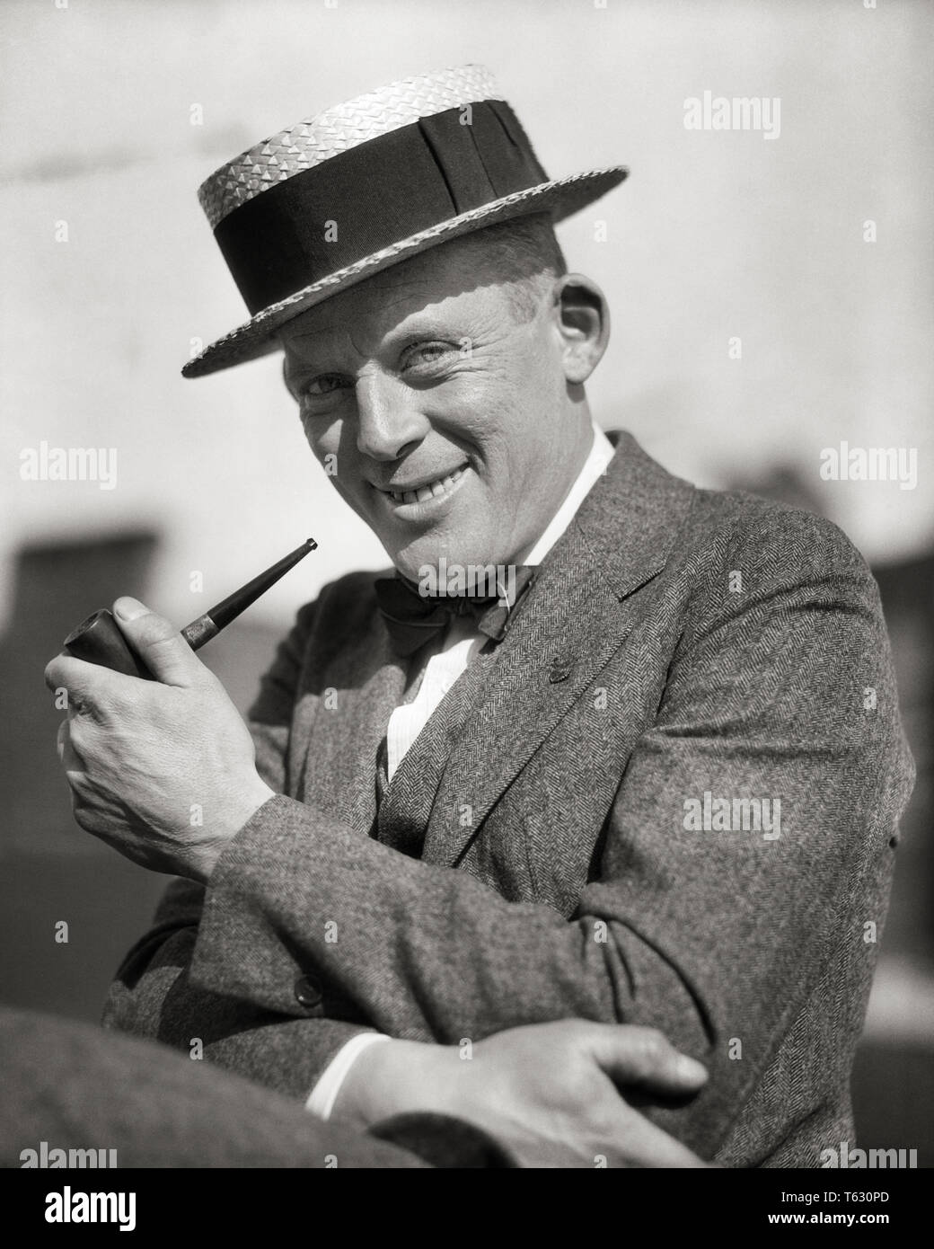 1920s PORTRAIT SMILING MAN SMOKING A PIPE WEARING A STRAW BOATER STYLE HAT SUIT BOW TIE LOOKING AT CAMERA - t380 HAR001 HARS JOY LIFESTYLE SATISFACTION PIPE COPY SPACE HALF-LENGTH PERSONS CHARACTER MALES CONFIDENCE EXPRESSIONS B&W SUMMERTIME EYE CONTACT SUIT AND TIE SELLING HAPPINESS CHEERFUL LEISURE PIPES STYLES SMILES SMOKER JOYFUL POPULAR STYLISH BOW TIE BOATER CADY FASHIONS MID-ADULT MID-ADULT MAN SALESMEN BLACK AND WHITE CAUCASIAN ETHNICITY HAR001 OLD FASHIONED Stock Photo