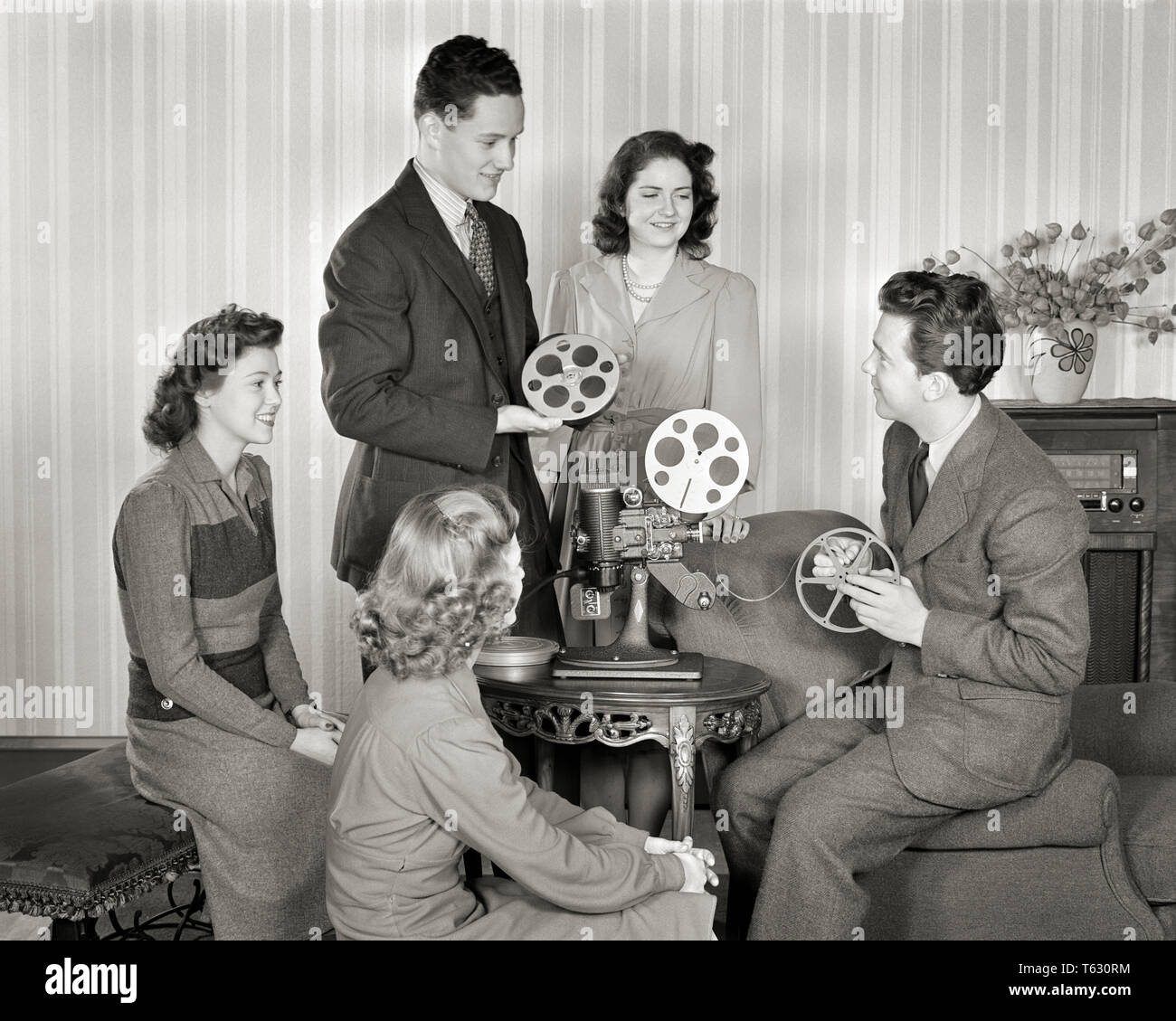 1940s GROUP OF SMILING YOUNG MEN AND WOMEN WITH REELS OF FILM SETTING UP  HOME MOVIE PROJECTOR - u591 HAR001 HARS OLD FASHION JUVENILE STYLE  COMMUNICATION YOUNG ADULT RELAXING LIFESTYLE FIVE FEMALES