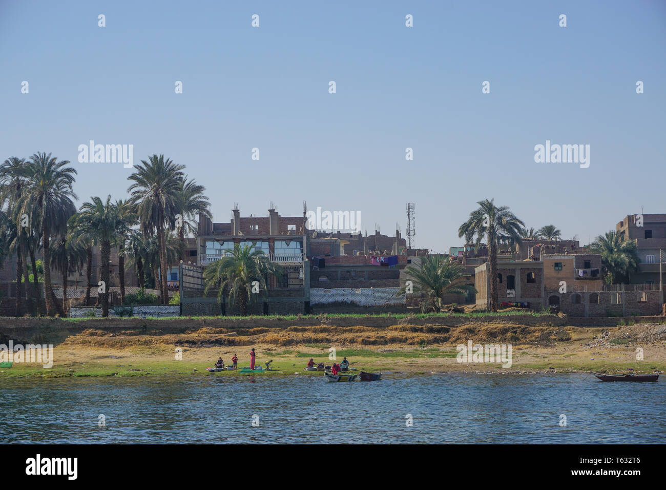 Nile River, Egypt: People, rowboats, houses, and date palm trees along the east bank of the Nile River. Stock Photo