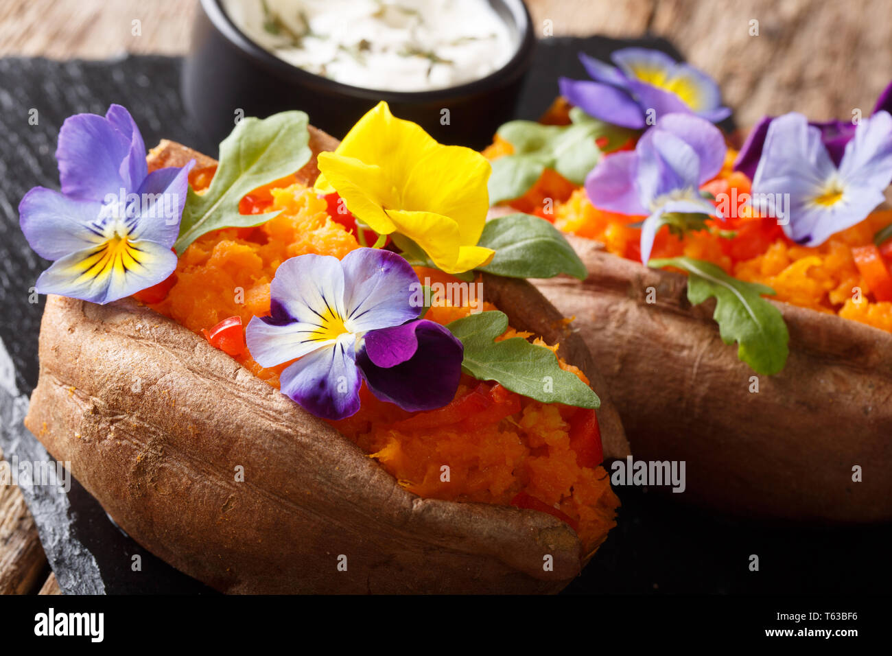 Baked yam with cream cheese decorated with edible flowers closeup on the table. horizontal