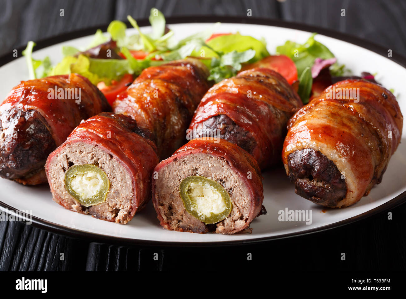 Smoked Armadillo eggs wrapped in bacon served with fresh salad close-up on a plate on the table. horizontal Stock Photo