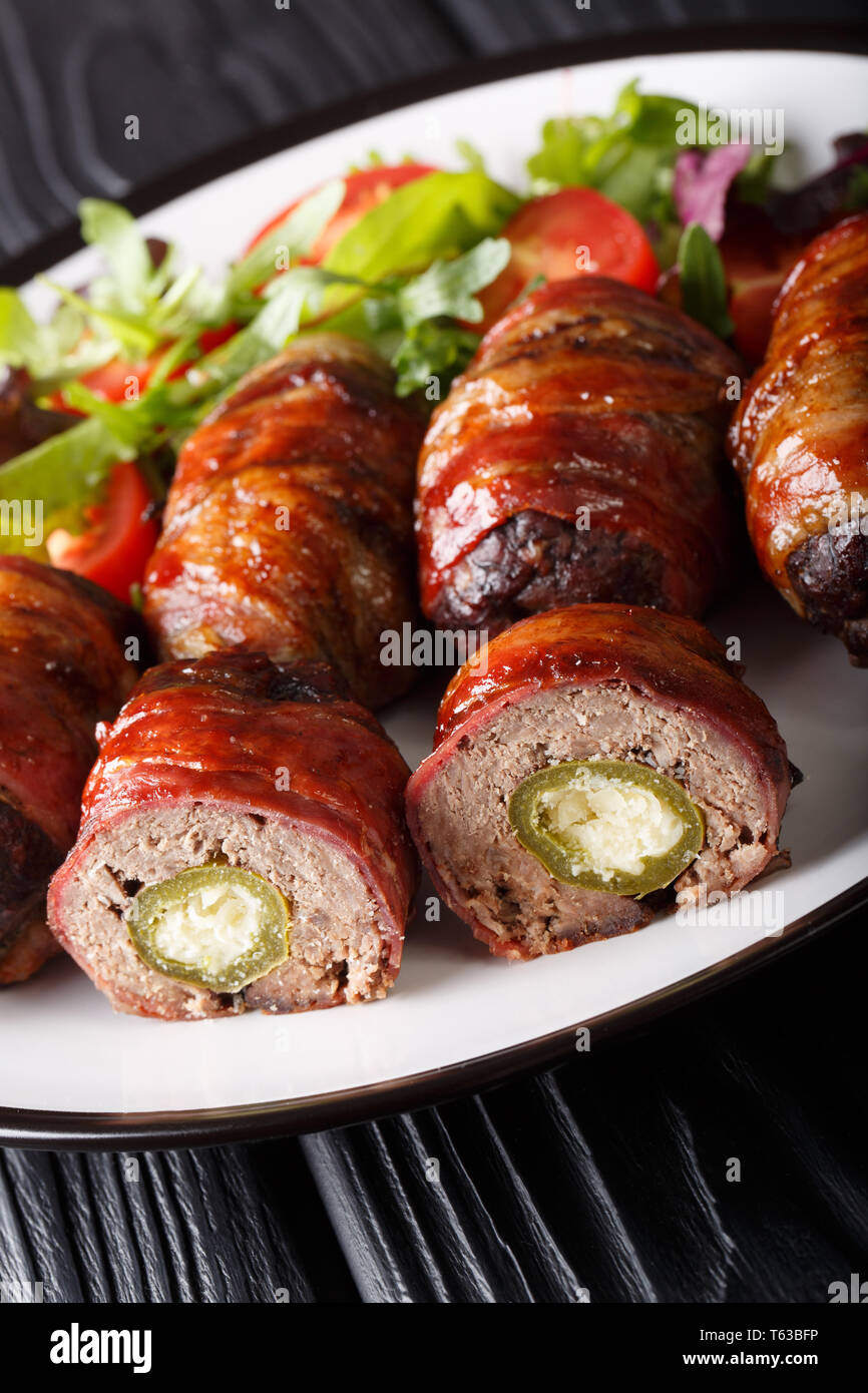 Armadillo eggs are a classic Texas BBQ staple served with salad close up on a plate on the table. vertical Stock Photo