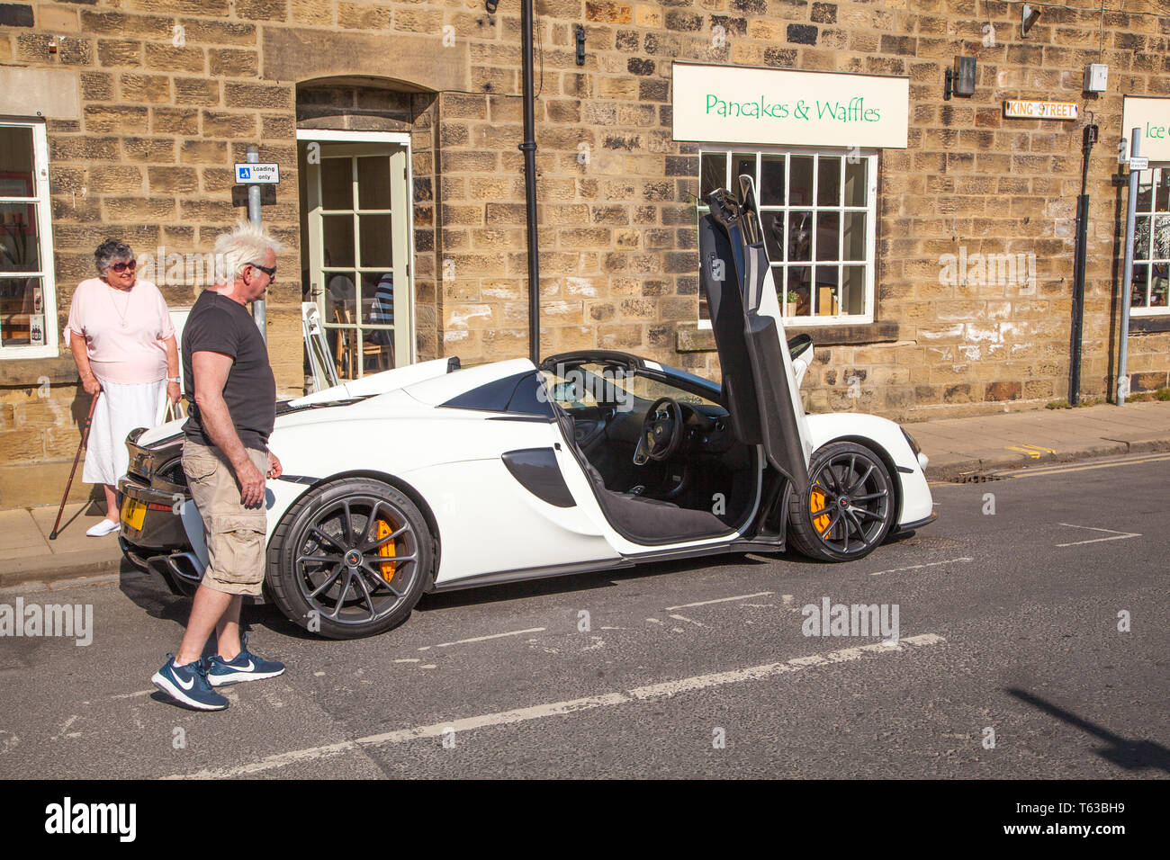 McLaren sports car being admired by two people standing at the roadside Stock Photo