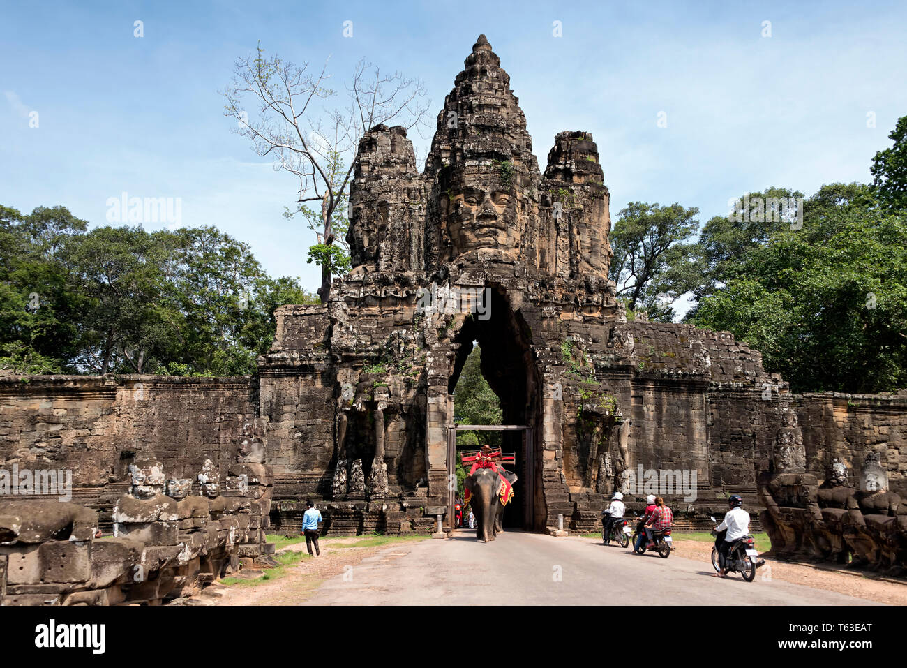 Elephants and locals on scooters crossing the South Gate of Angkor Thom, in Siem Reap, Cambodia Stock Photo