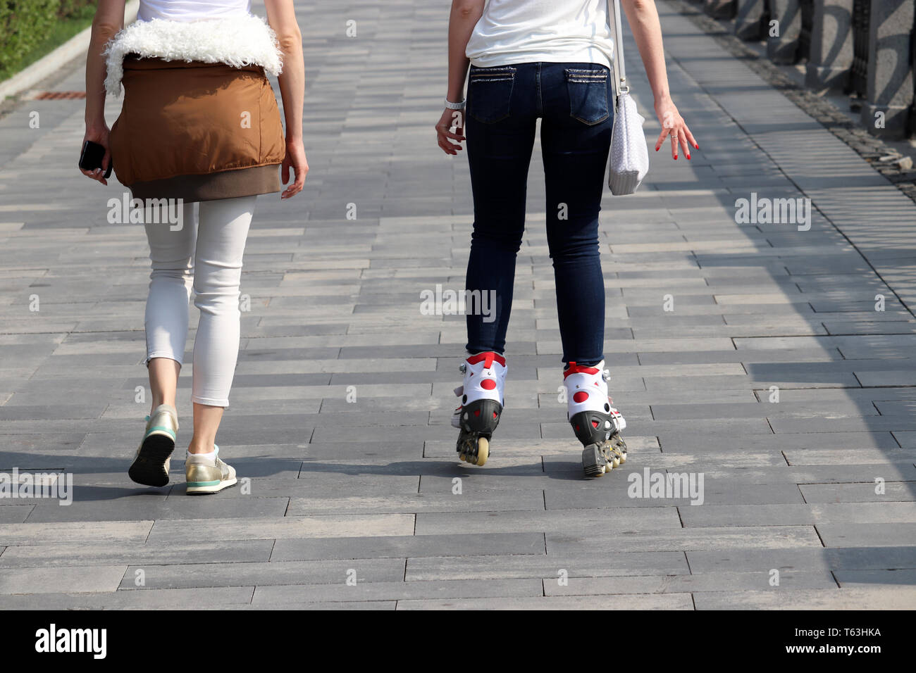 Riding on roller skates, two girls walking on the street. Concept of youth, sport, lifestyle Stock Photo