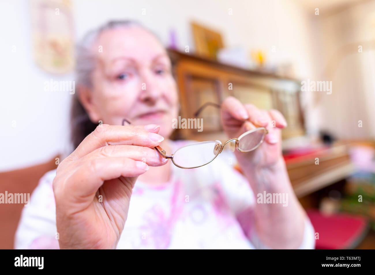 An old woman puts on her glasses Stock Photo