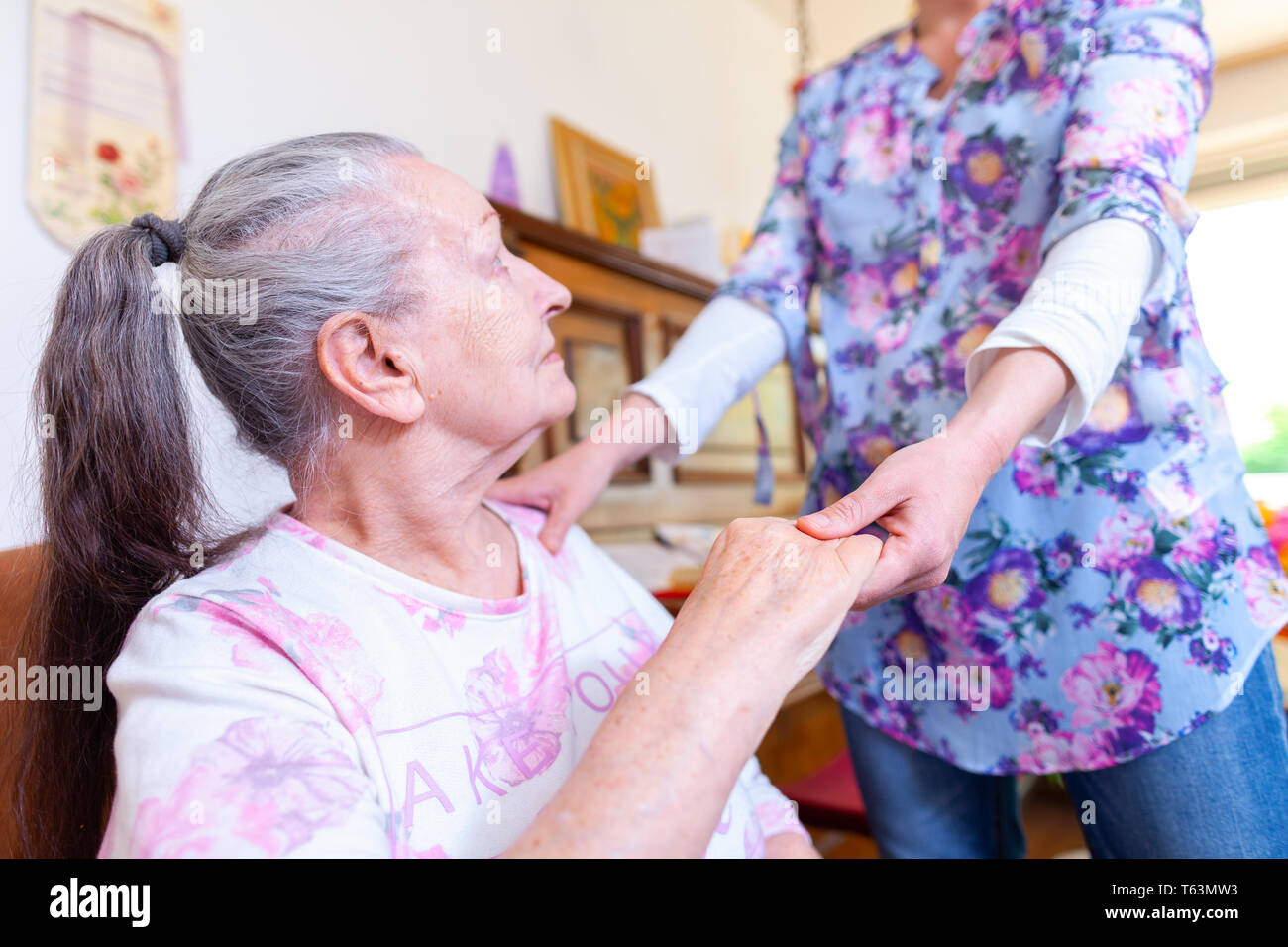 A young woman is holding the hand of an old woman Stock Photo - Alamy