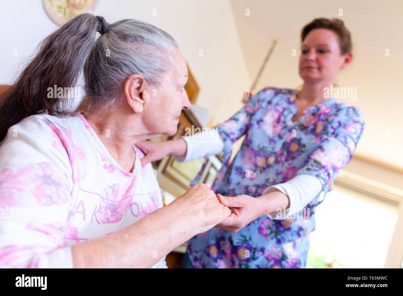 A young woman is holding the hand of an old woman Stock Photo - Alamy