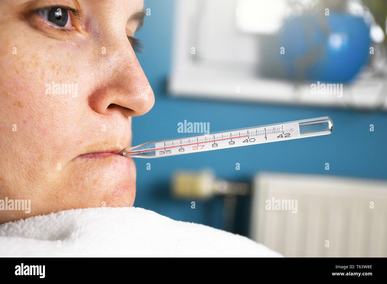 Close up of ill woman with flu and thermometer in her mouth measuring body temperature reaching 40 degrees celsius Stock Photo