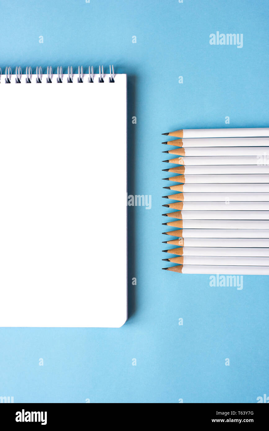 Pencils and a notebook on blue surface. Close up. Copy space for text Stock Photo