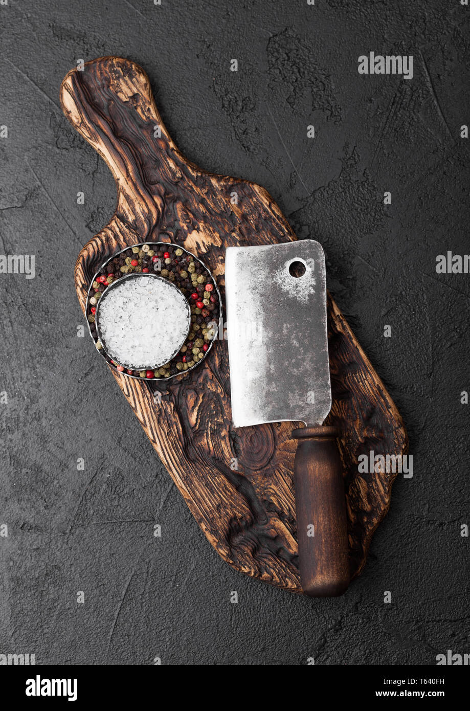 Vintage meat knife hatchet on vintage chopping board and black stone