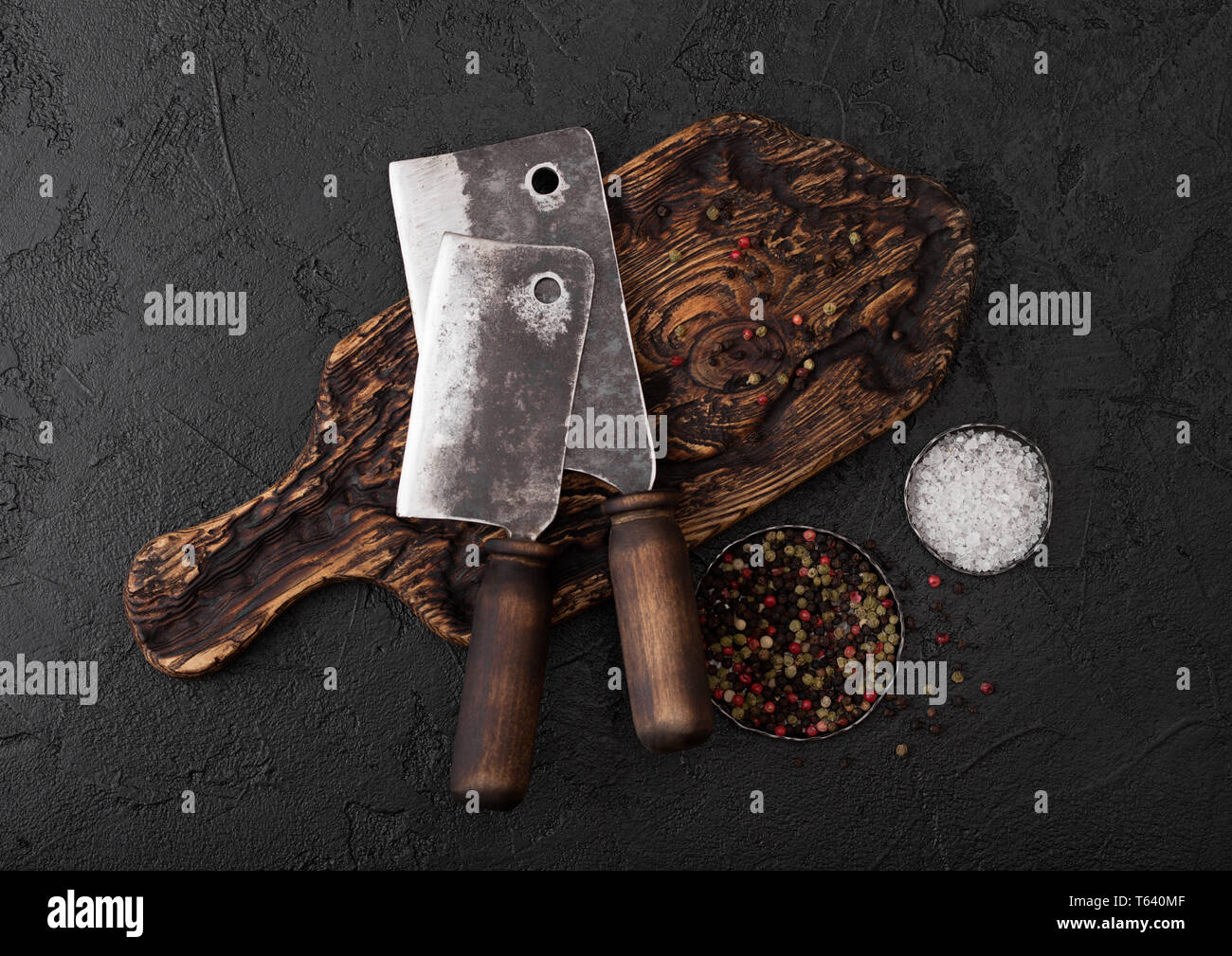 Vintage meat knife hatchet on vintage chopping board and black stone