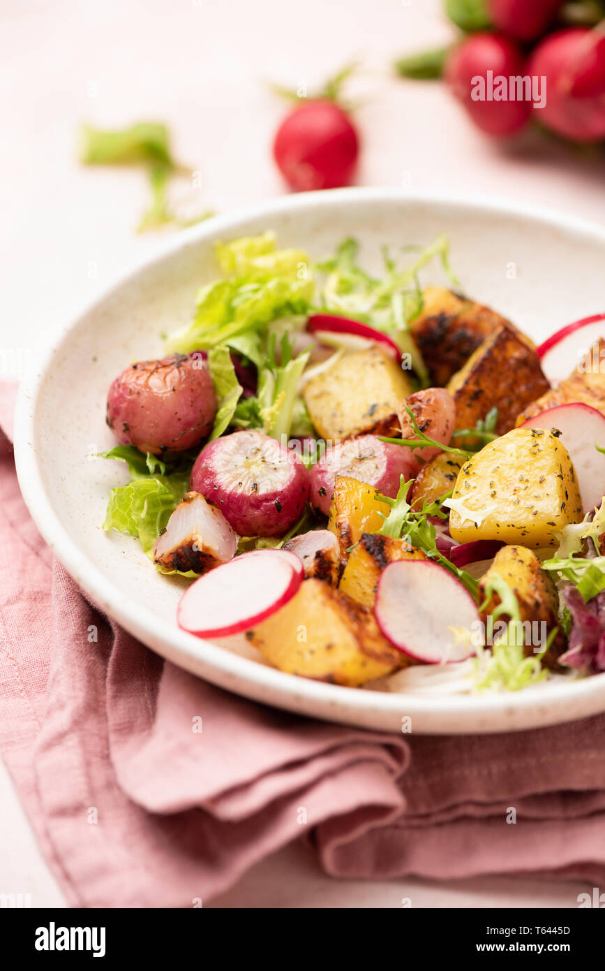 Healthy spring salad with potato, radish and green leaf salad on plate. Roasted vegetables salad. Closeup view, selective focus Stock Photo