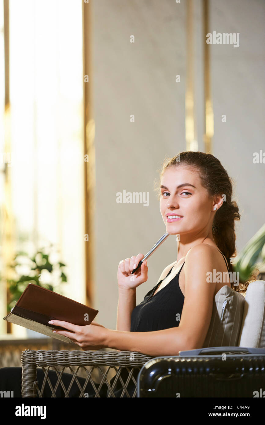 Cheerful woman filling journal Stock Photo
