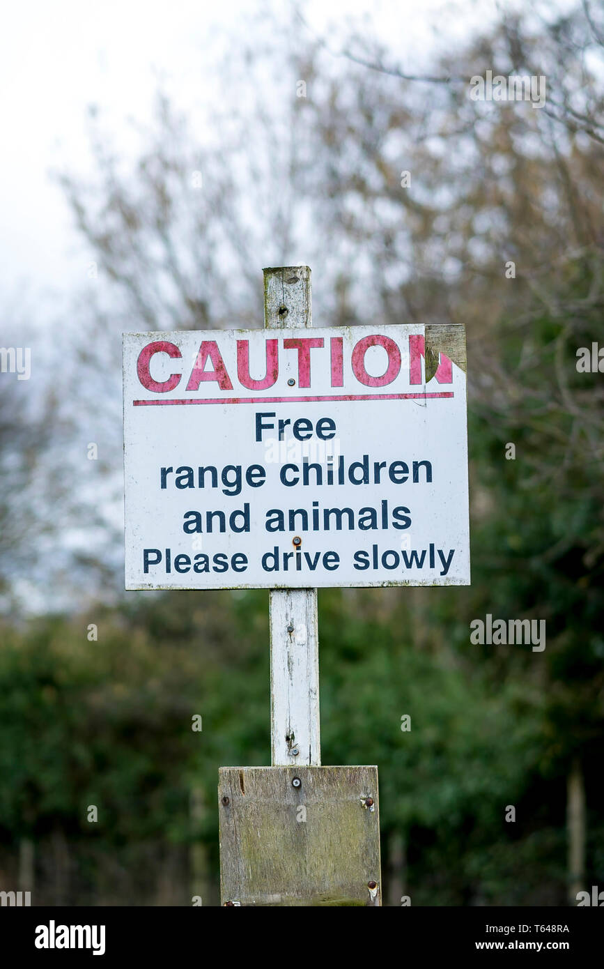 Public notice warning motorists to Please Drive Slowly due to Free Range Children and Animals in the area. Good advice with British sense of humour! Stock Photo