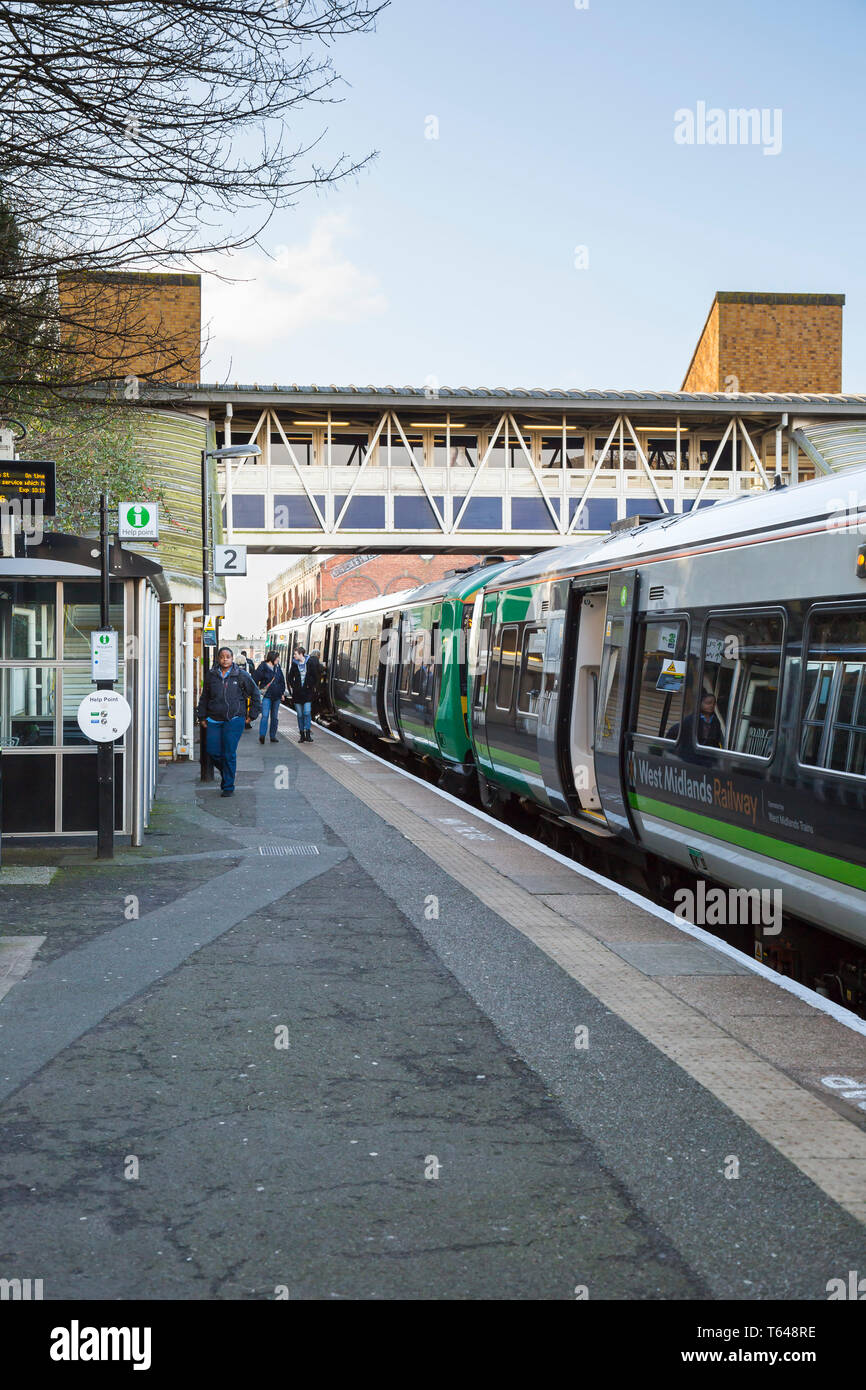 Vertical shot of early morning passengers on the platform at a UK railway station. Stock Photo