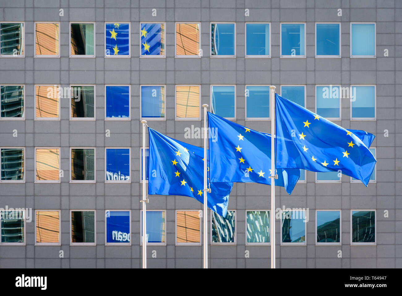Three flags of the European Union blowing in the wind in front of the Berlaymont building, seat of the European Commission in Brussels, Belgium. Stock Photo