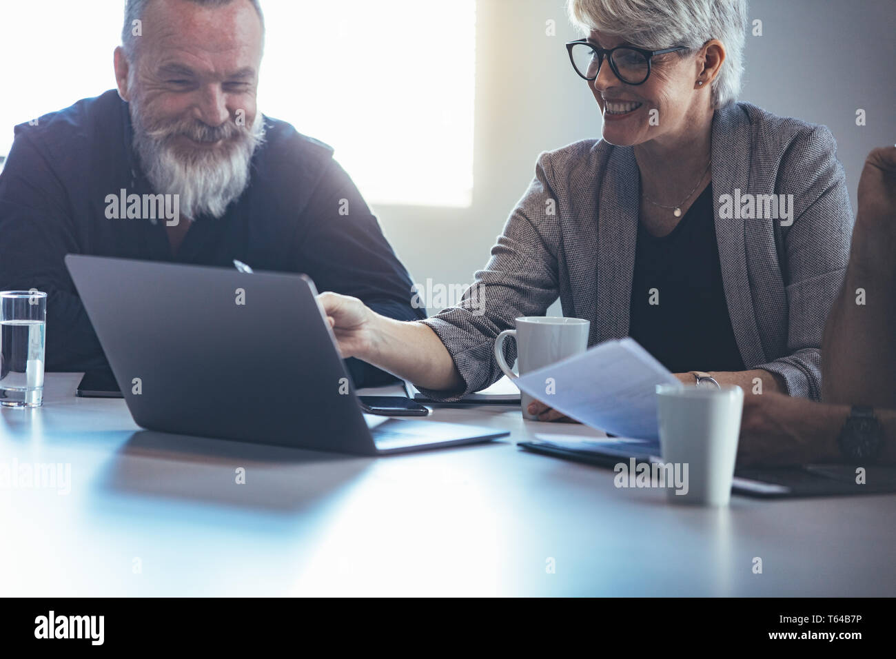 Mature business woman explaining business plan to colleagues. Mature manager planning new strategy with colleagues in meeting. Stock Photo