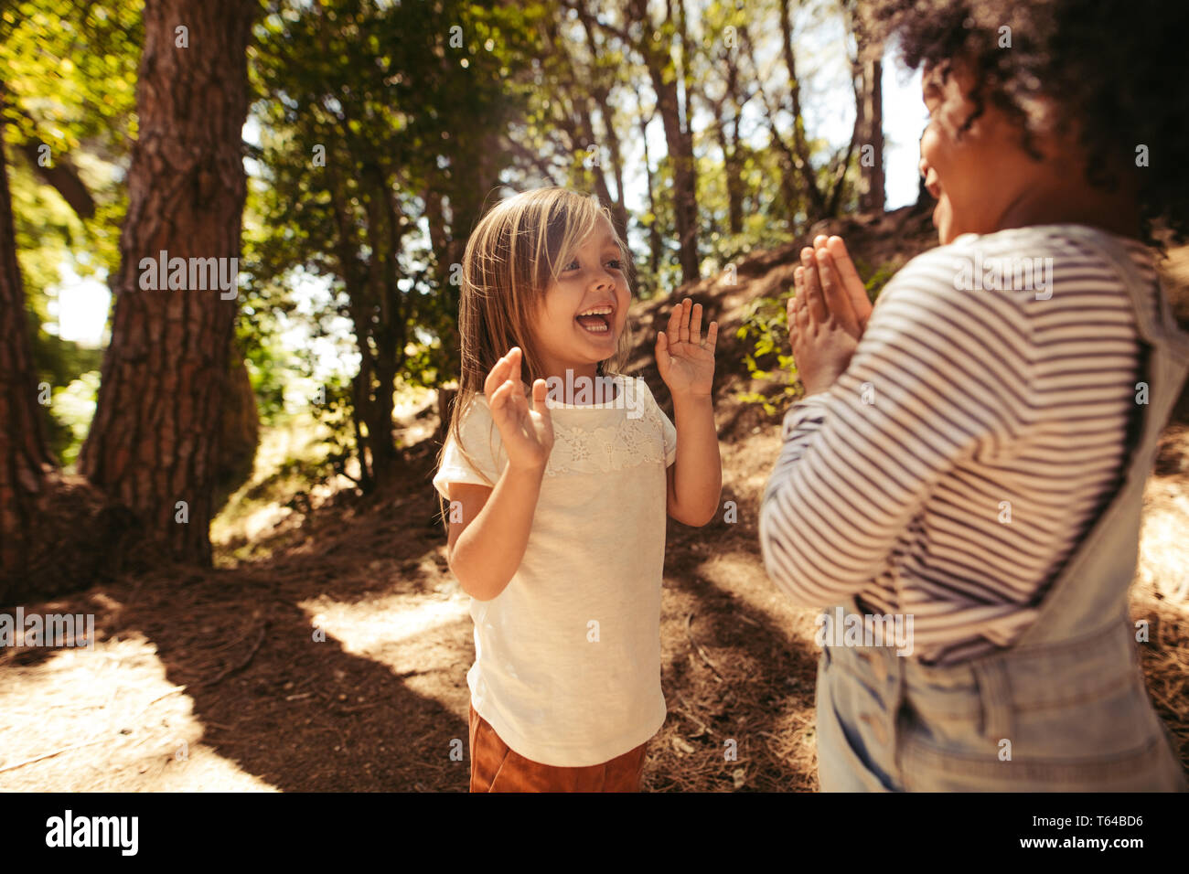 Cheerful girls playing clapping games in forest. Cute children playing games in a park. Stock Photo