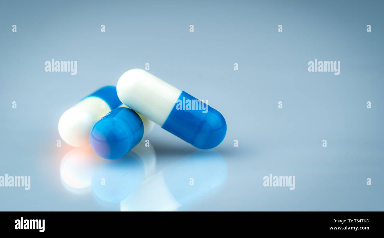Blue and white capsule pills on gradient background. Global healthcare concept. Antibiotics drug