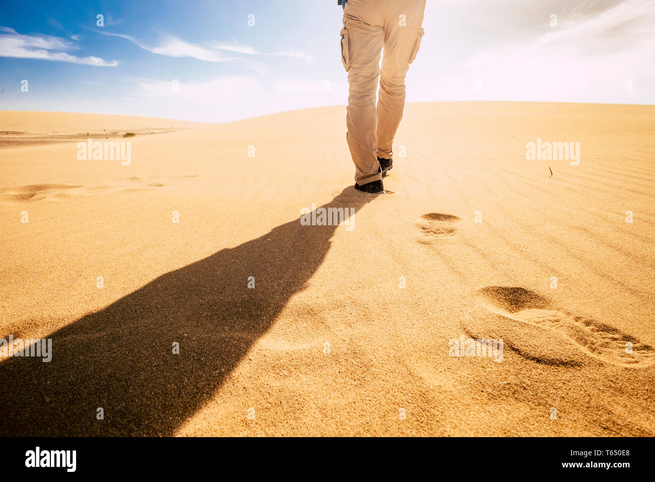 Travel and explore people concept with man viewed from back walking in tha sand of the desert dunes alone under the sunset - summer holiday vacation a Stock Photo