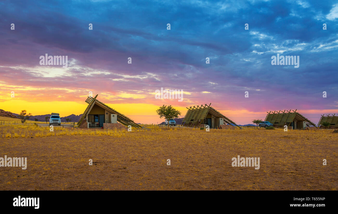 Sunrise above small chalets of a desert lodge near Sossusvlei in Namibia Stock Photo