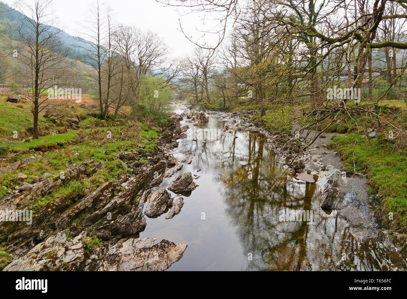 The rock strewn River Mawddach flows between tree lined banks in the