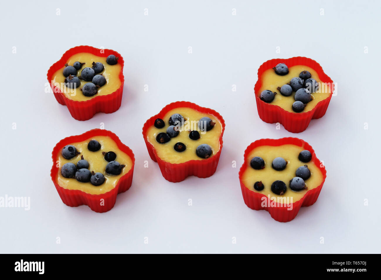 Preparation for baking muffins with currants, dough is spread out into silicone molds, the top view Stock Photo