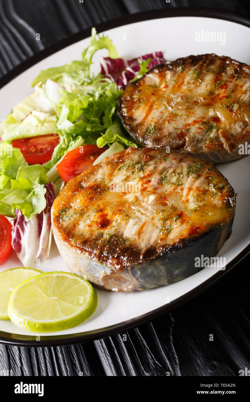 grilled sturgeon steaks with vegetable salad closeup on a plate on the table. vertical Stock Photo