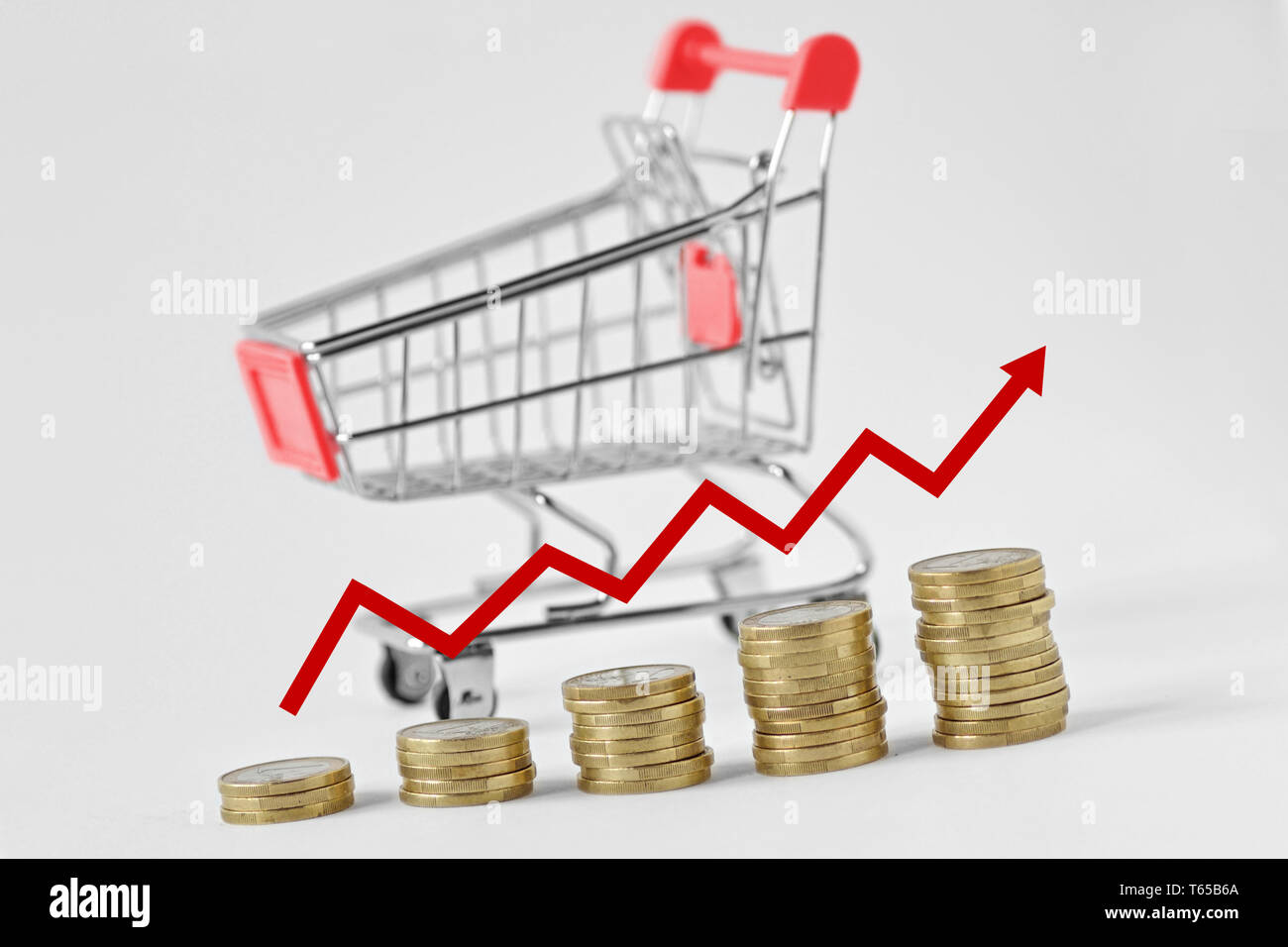 Pile of coins with arrow and shopping cart on the background - Concept of increasing purchases Stock Photo