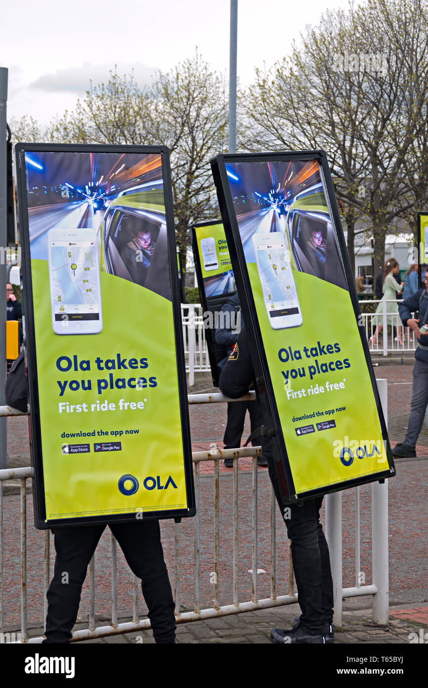 People with large sign on their back advertising the Ola taxi app Stock Photo