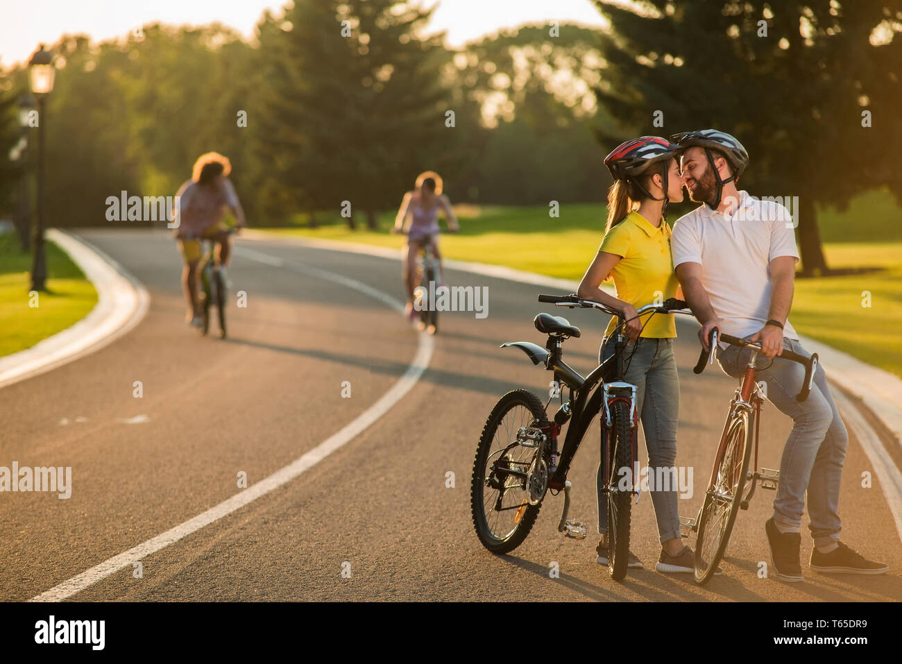 Happy couple kissing during a bicycle ride outdoors. Stock Photo