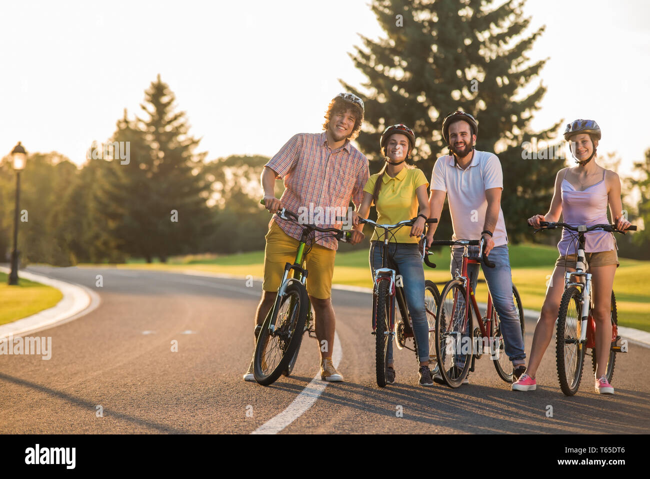 Four happy friends on bikes outdoors. Stock Photo