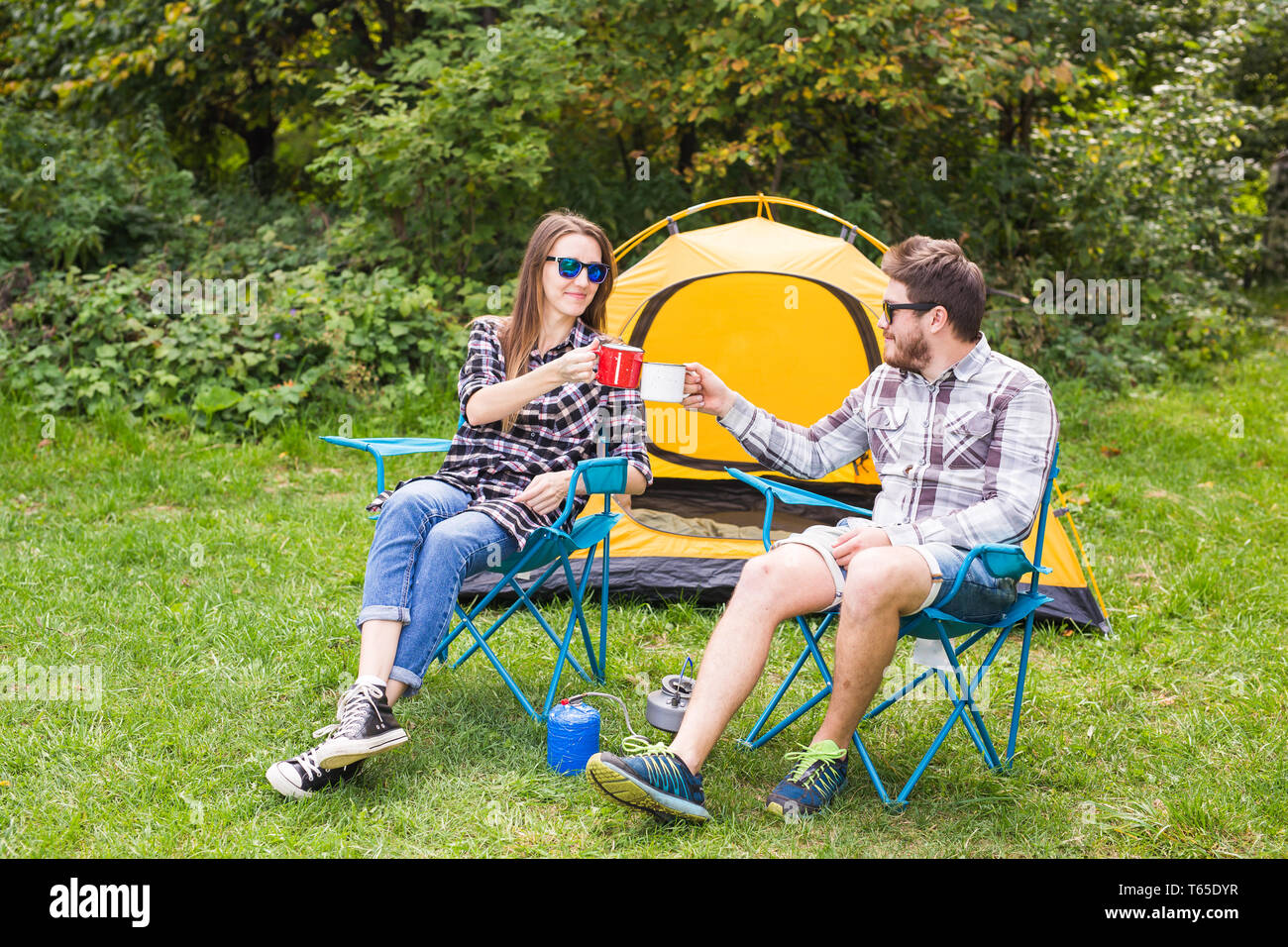 people, summer tourism and nature concept - young couple sitting near a ...