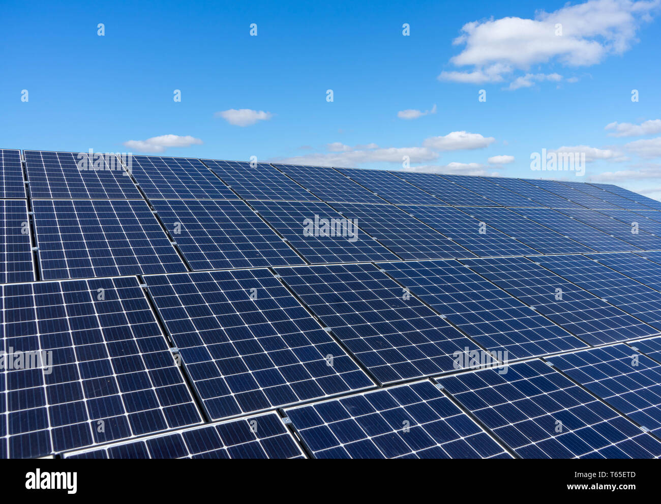 Solar panels on a roof with a blue sky and white clouds background Stock Photo