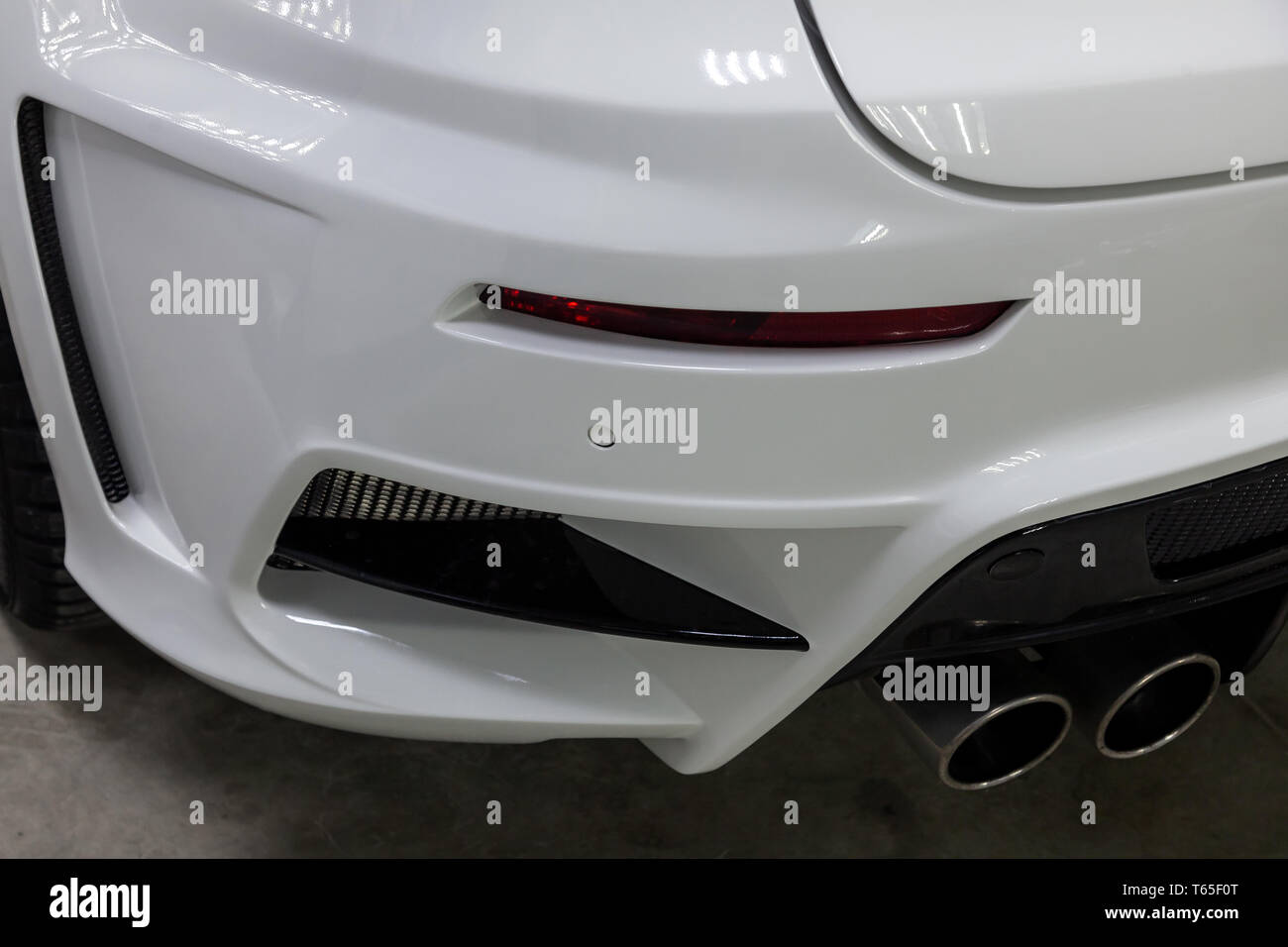 The rear bumper of a tuned car is white with a double exhaust nozzle, a ...