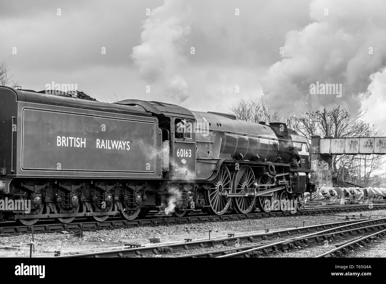 Black & white side view of vintage UK steam locomotive Tornado leaving Kidderminster heritage railway station, Spring 2018. Vintage train departure. Stock Photo