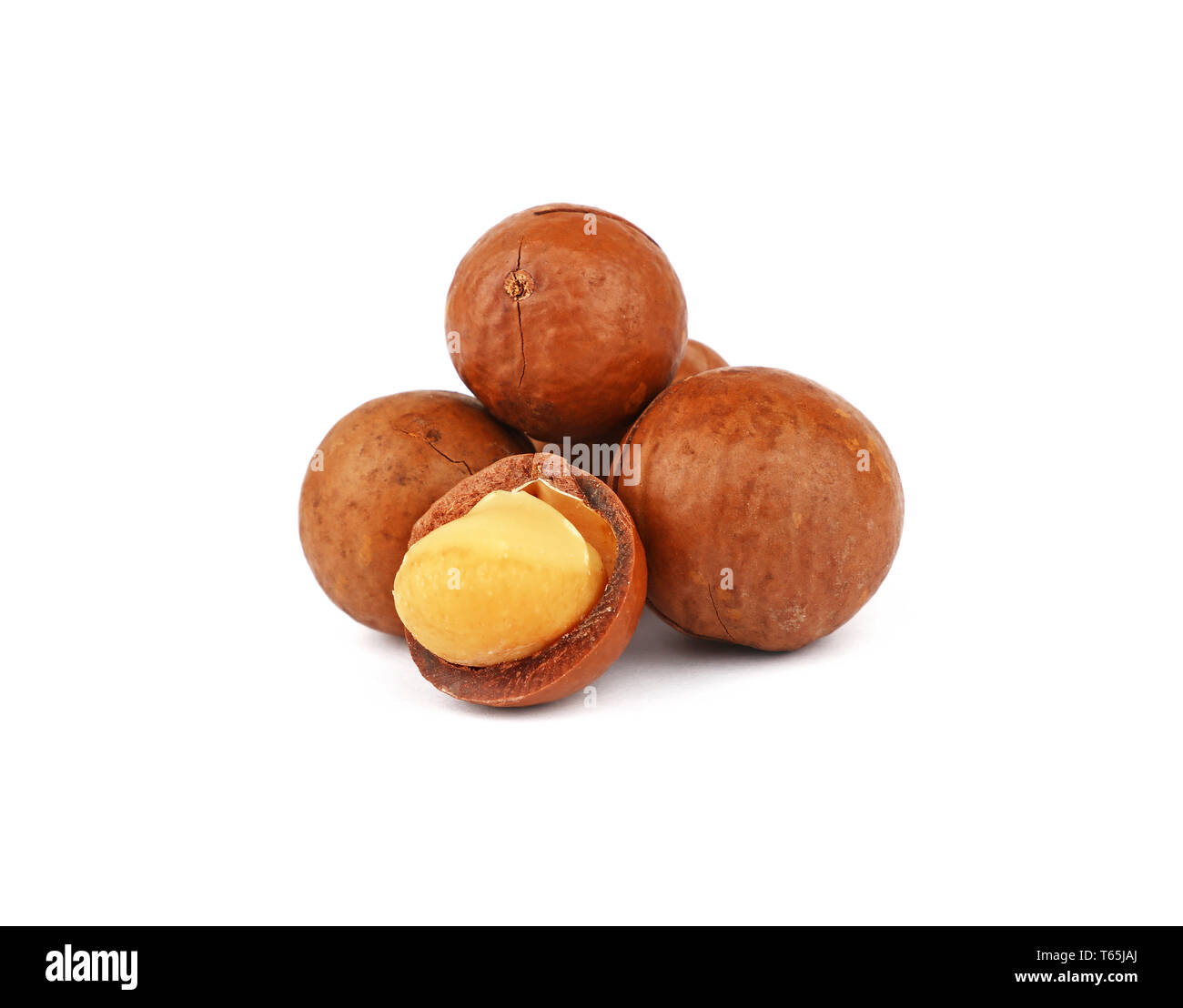 Close up group of several unshelled macadamia nuts and one open kernel isolated on white background, low angle side view Stock Photo
