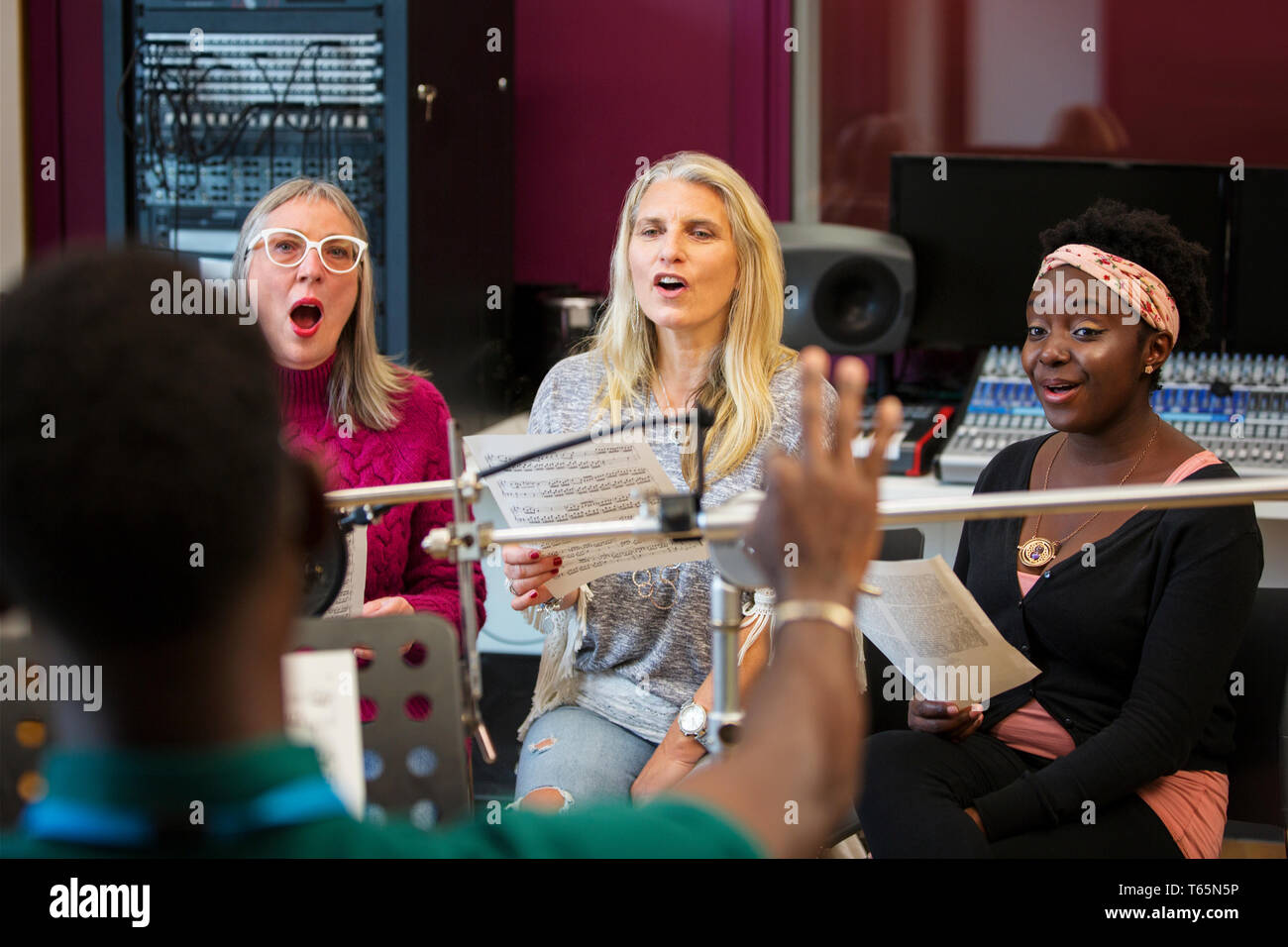 Womens choir with sheet music singing in music recording studio Stock Photo