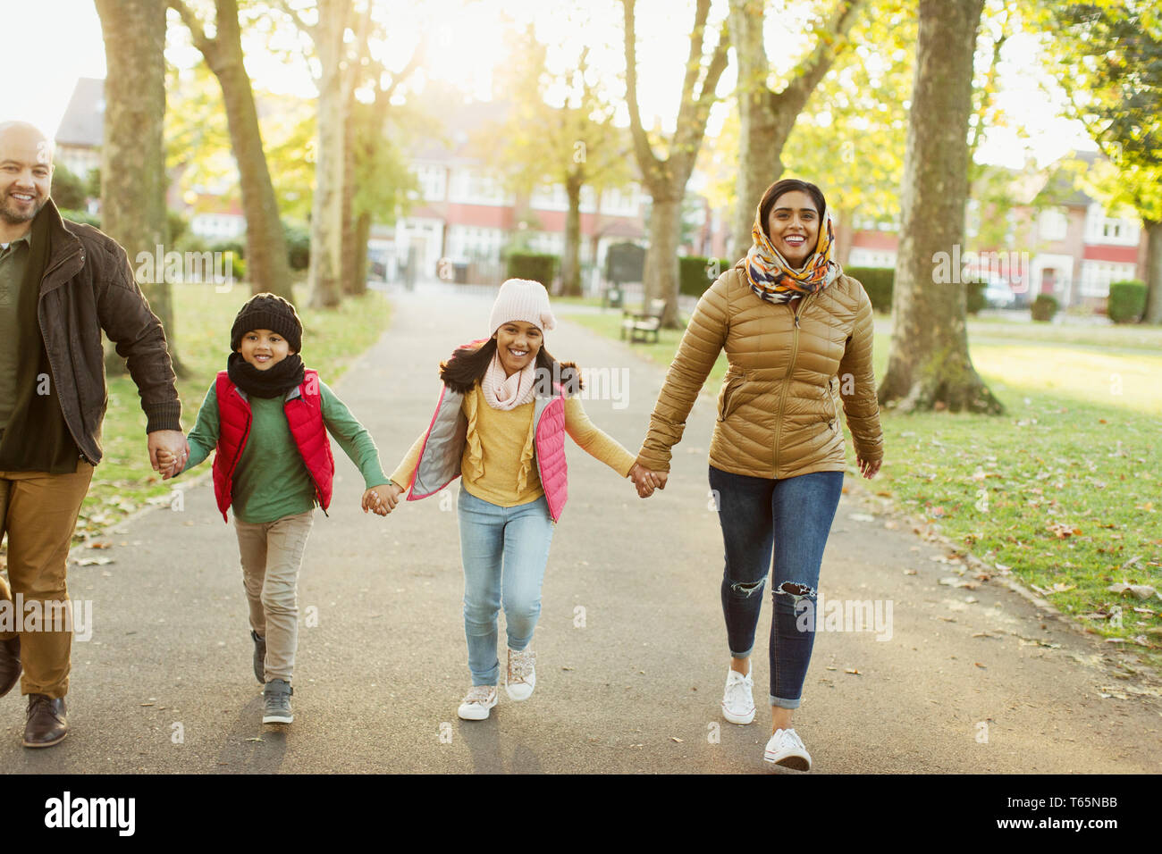 Happy Muslim family holding hands, walking in autumn park Stock Photo