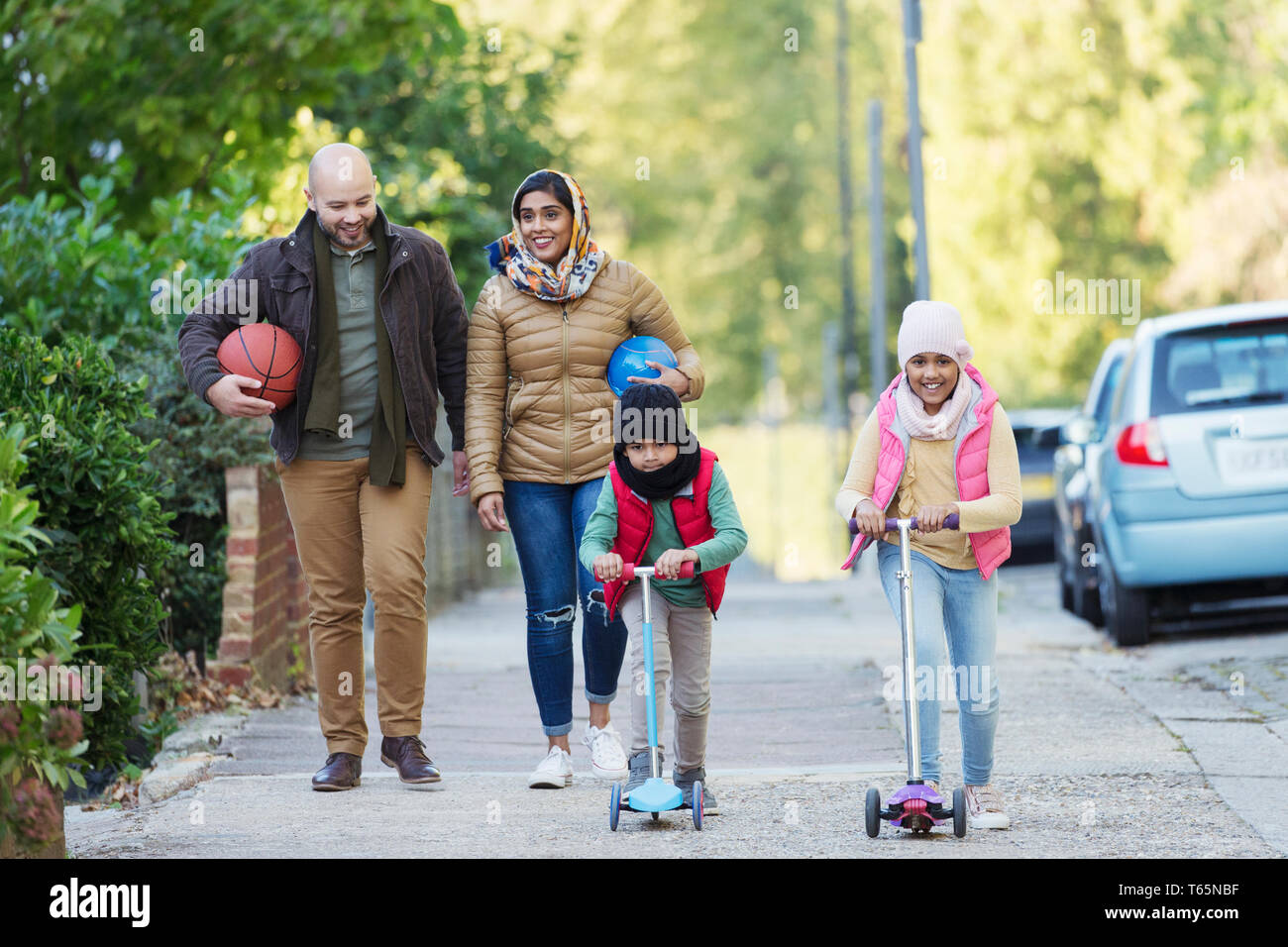 Muslim family watching and riding scooter on sidewalk Stock Photo
