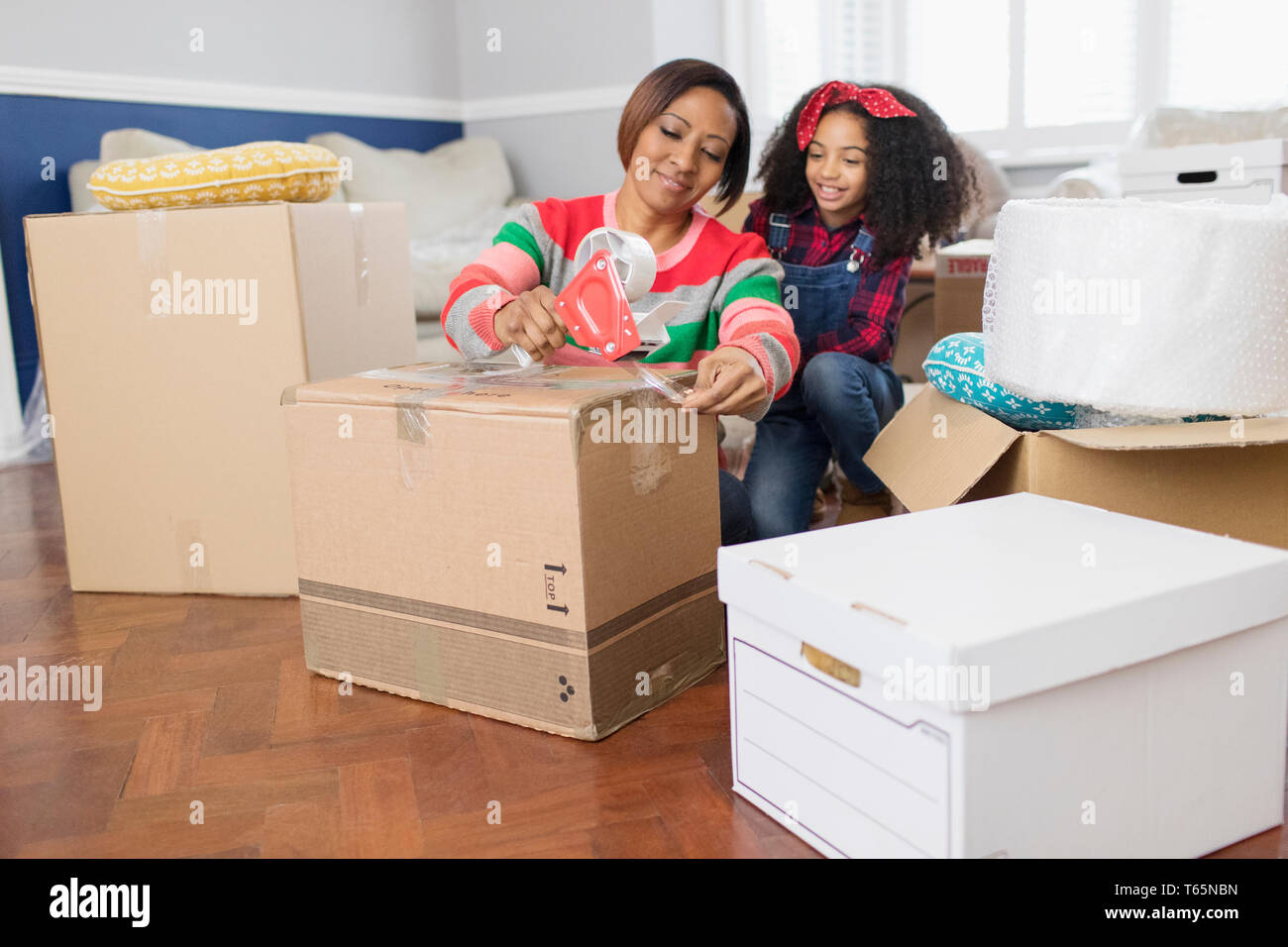 Mother and daughter taping moving boxes, moving house Stock Photo