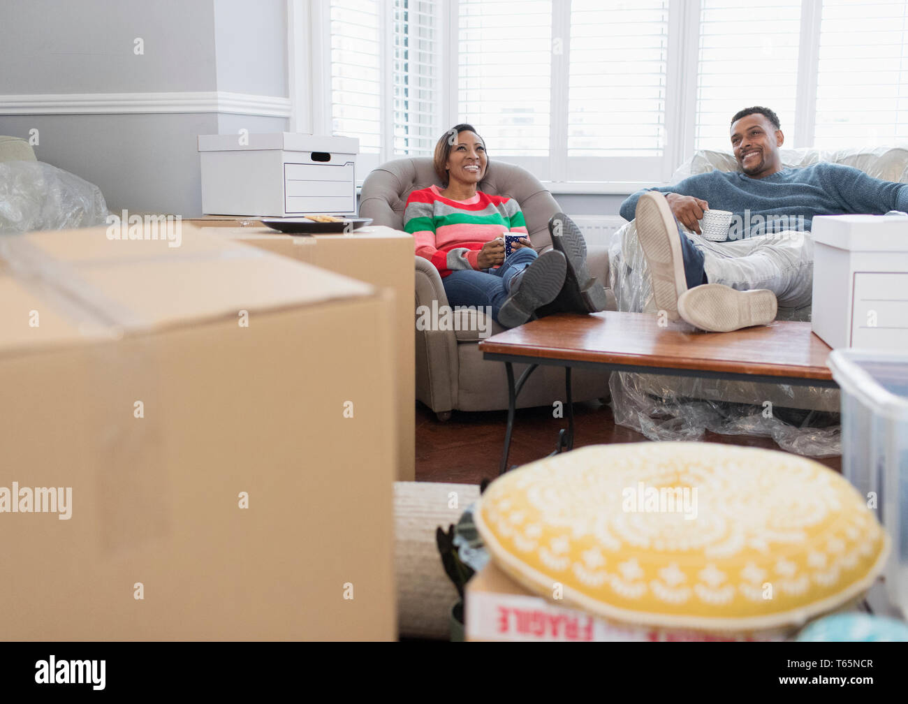 Happy couple moving house, taking a break and drinking tea Stock Photo