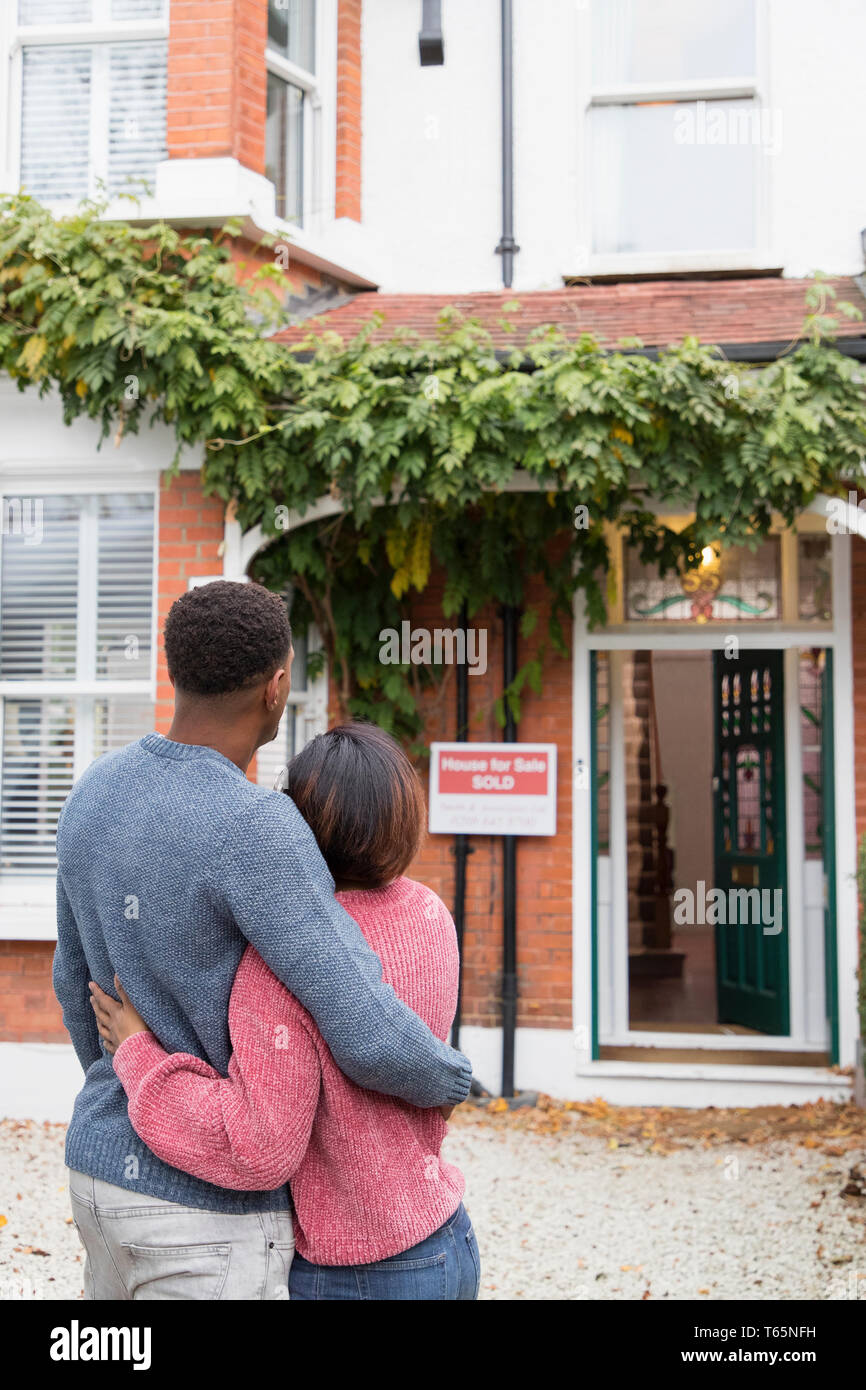 Happy couple hugging outside new house Stock Photo