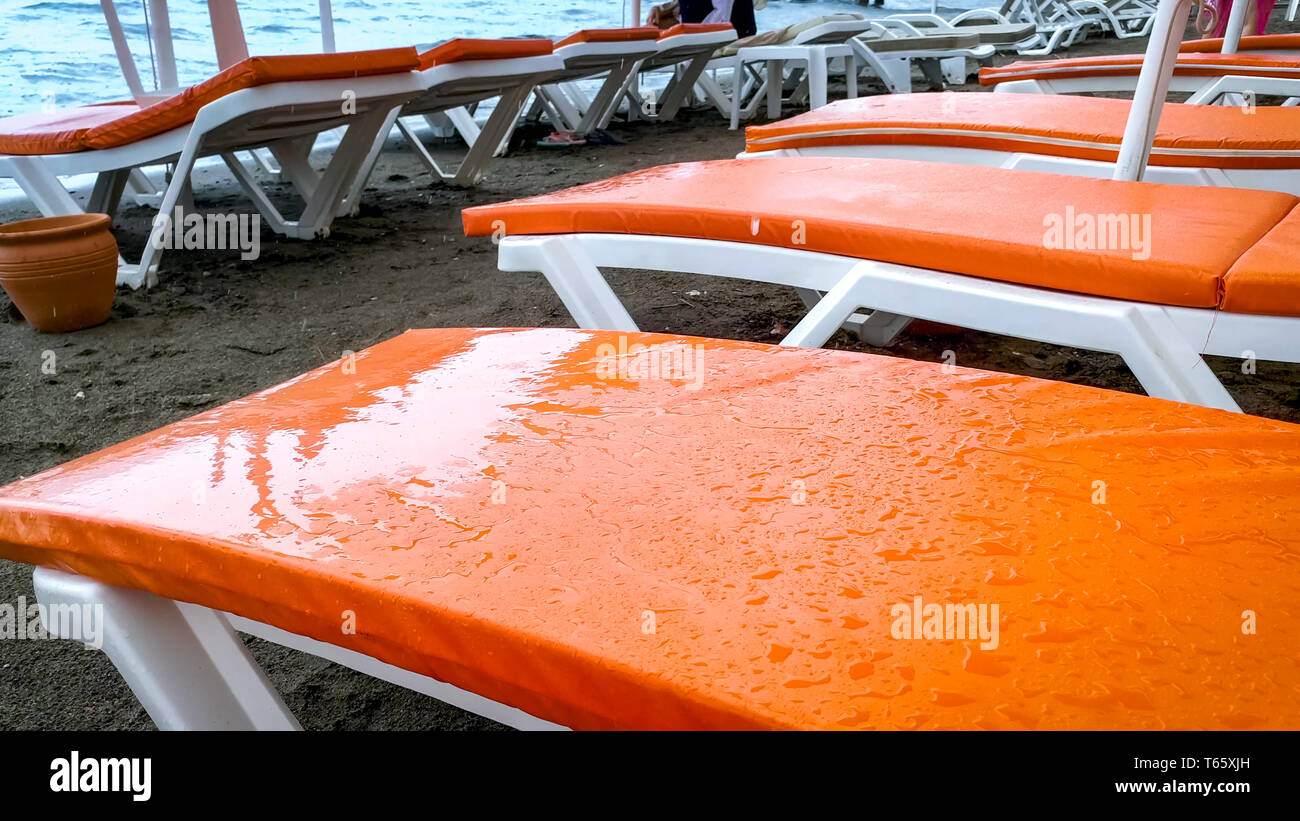 Closeup image of wet sunbeds on the beach during storm Stock Photo Alamy