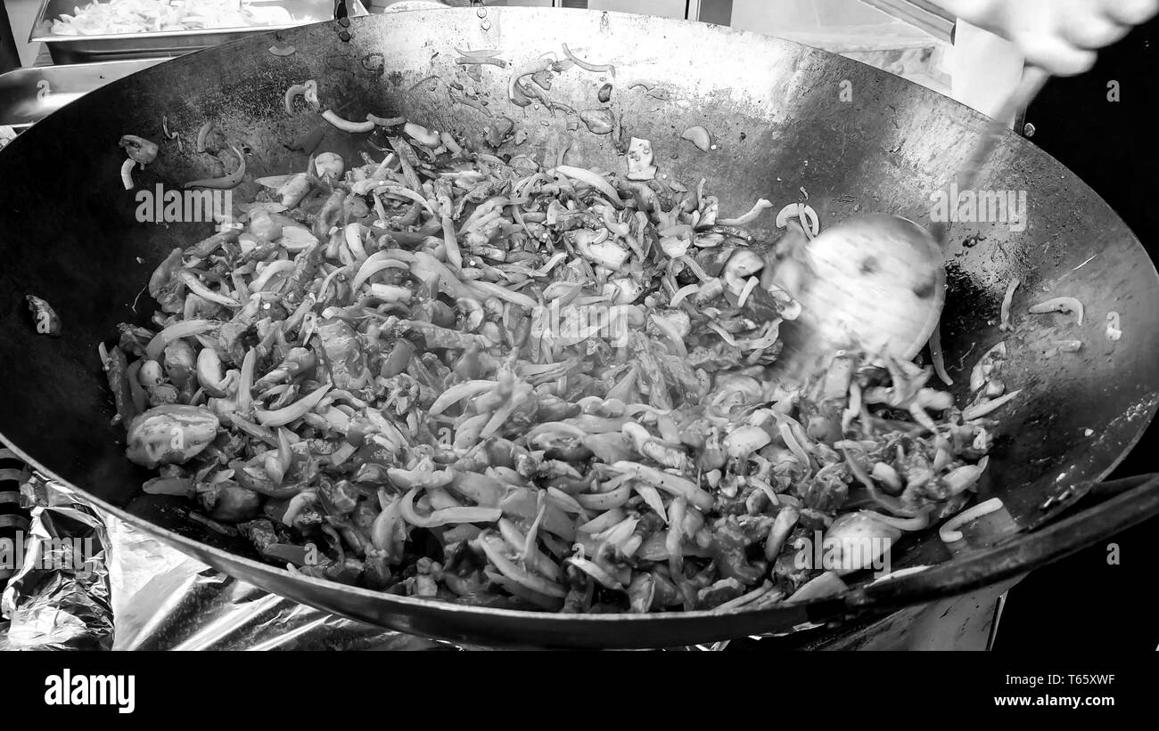 Black and white image of cooking vegetables in wok pan at outdoor cafe Stock Photo