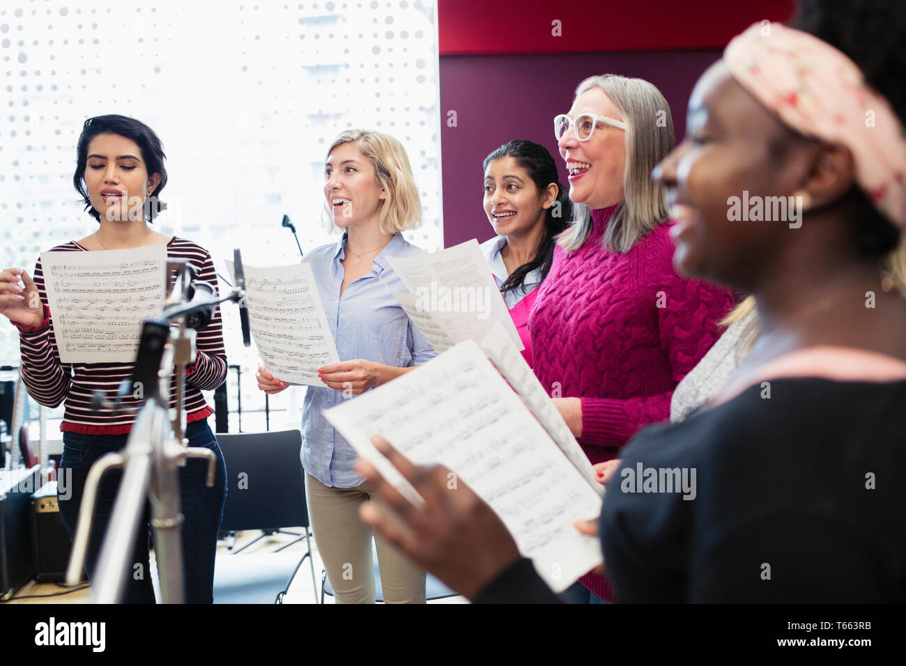 Womens choir with sheet music singing in music recording studio Stock Photo