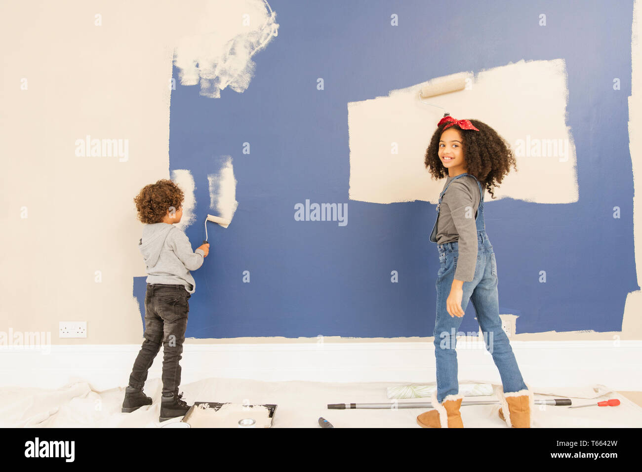 Portrait happy brother and sister painting wall Stock Photo