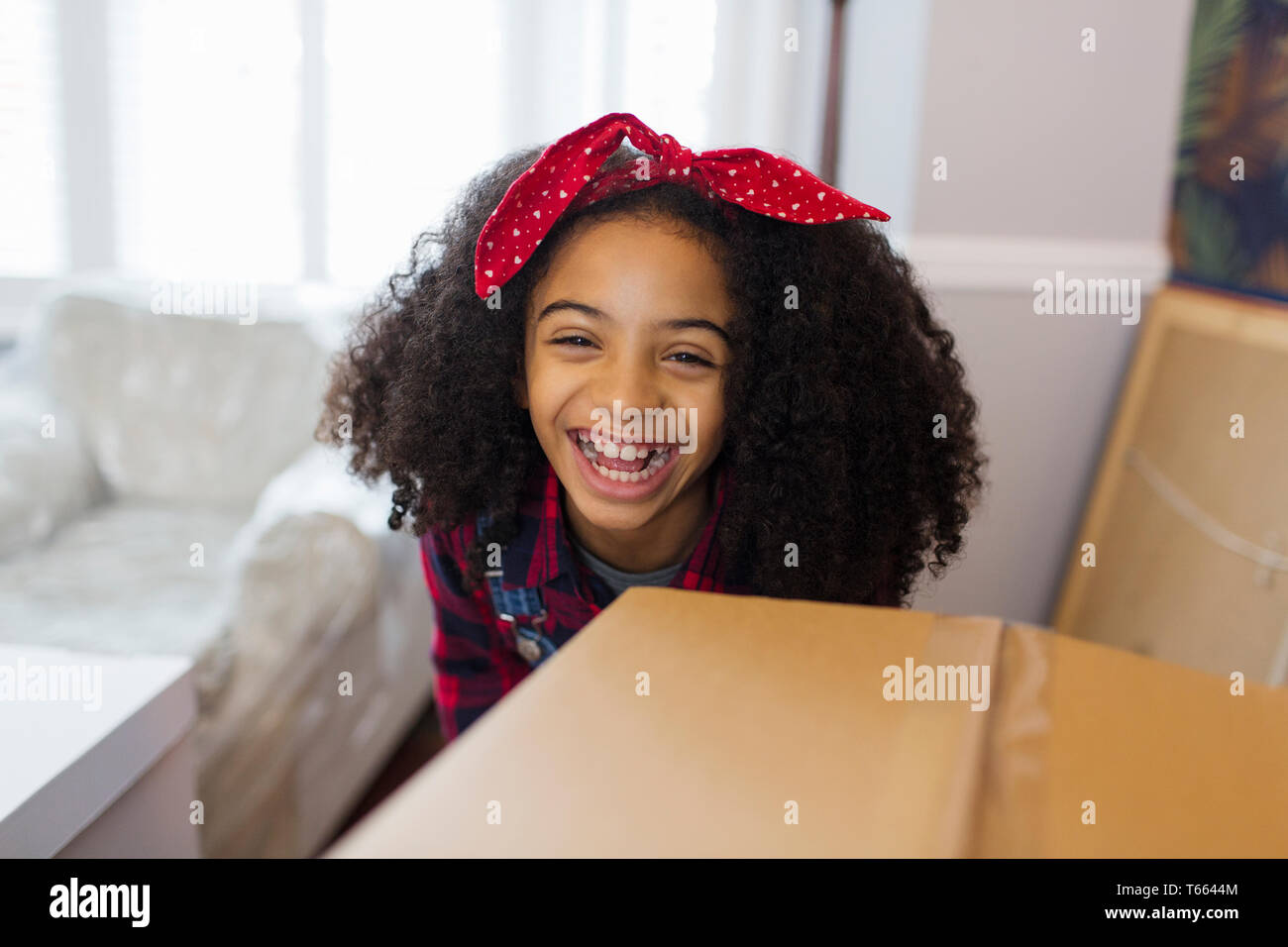 Portrait happy girl behind cardboard box, moving into new house Stock Photo